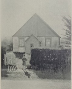 Old photo of a young boy standing in front of the church.